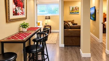 A dining area with a table and chairs, a sofa, and a painting on the wall.