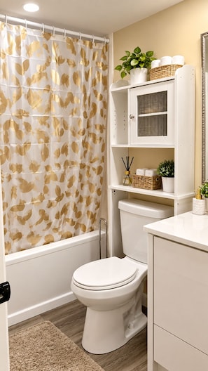 A bathroom with a toilet, a shower curtain with a leaf pattern, a sink, and a mirror. - Cozy 1 BDR close downtown university Ottawa cite collégiale Le CST (Ottawa)