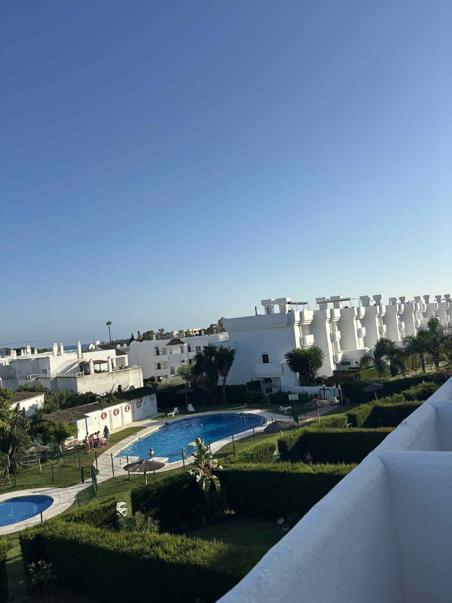 Zona residencial con piscina, edificios blancos y cielo despejado.