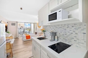 A modern kitchen with white cabinetry, a built-in microwave, and a black stove. - @ ML - Bright Waikiki Canal View + Relaxing Breeze (Honolulu)
