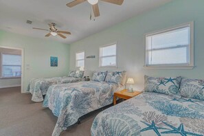 A room with two beds, a ceiling fan, and multiple windows with blinds. - Beach House Steps to Beach (Bolivar Peninsula)