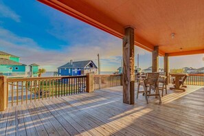 A wooden deck with a railing, overlooking a beach with houses in the background. - Beach House Steps to Beach (Bolivar Peninsula)