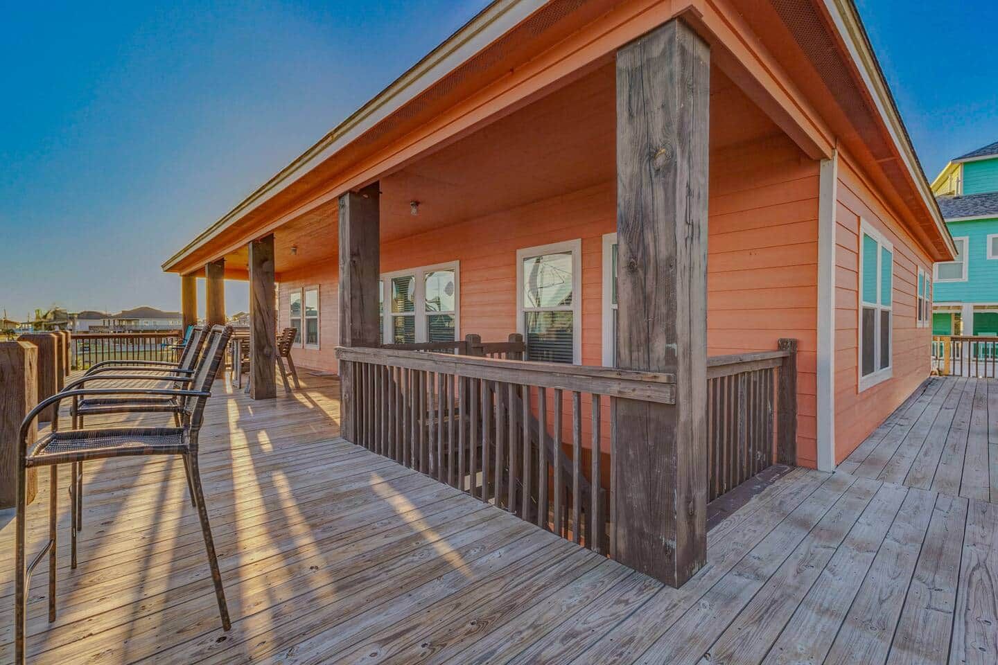A wooden deck with chairs, a railing, and a building with windows.