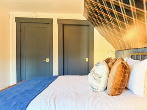 A bedroom with a bed, pillows, a headboard, and two doors. - Downtown - Hot Tub, Speakeasy, Grill, Game Room, Fireplace (Ludlow)