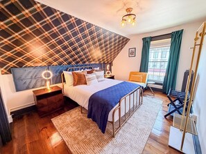 A bedroom with a bed, bedside tables, a hanging chair, a window with curtains, and a ceiling light fixture. - Downtown - Hot Tub, Speakeasy, Grill, Game Room, Fireplace (Ludlow)