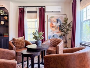 A living room with leather sofas, a round table, and a potted plant. - Downtown - Hot Tub, Speakeasy, Grill, Game Room, Fireplace (Ludlow)
