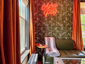 A room with a neon sign reading 'Aper Play,' a green sofa, a small table with a keyboard, and curtains. - Downtown - Hot Tub, Speakeasy, Grill, Game Room, Fireplace (Ludlow)