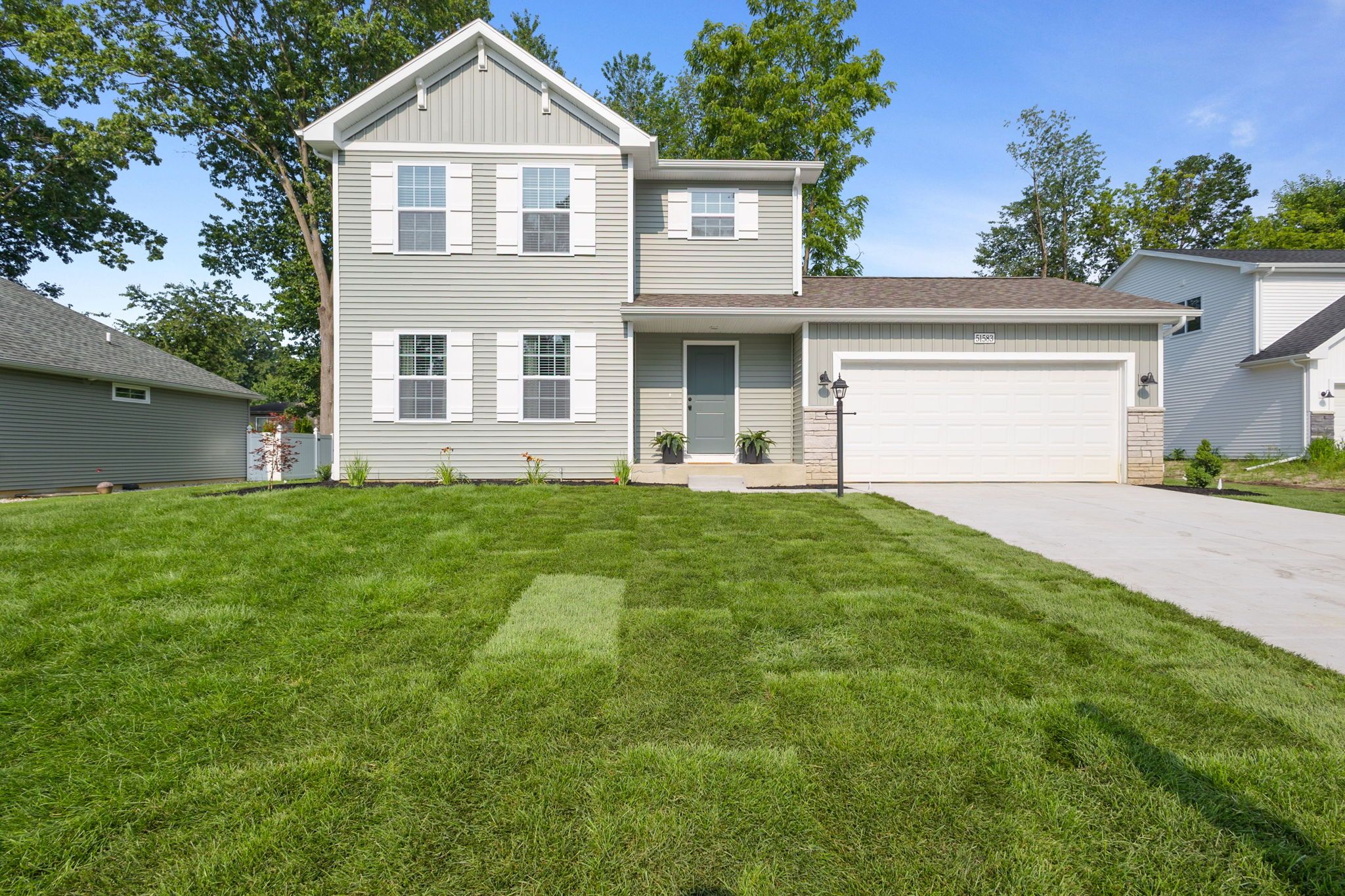 A two-story house with a garage, a well-maintained lawn, and a clear sky.