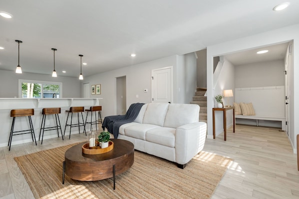 A modern living room with a white sofa, wooden coffee table, and bar stools. - New 4 Bed 2 and a Half Bath Near ND Campus (South Bend)