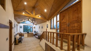 Un interior espacioso con una escalera de madera, una zona de recepción y amplios ventanales que ofrecen vistas.