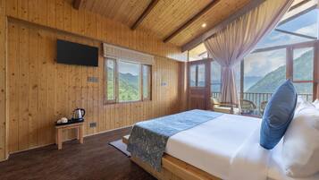 Una habitación de madera con una cama, una mesa con un hervidor y un televisor en la pared.