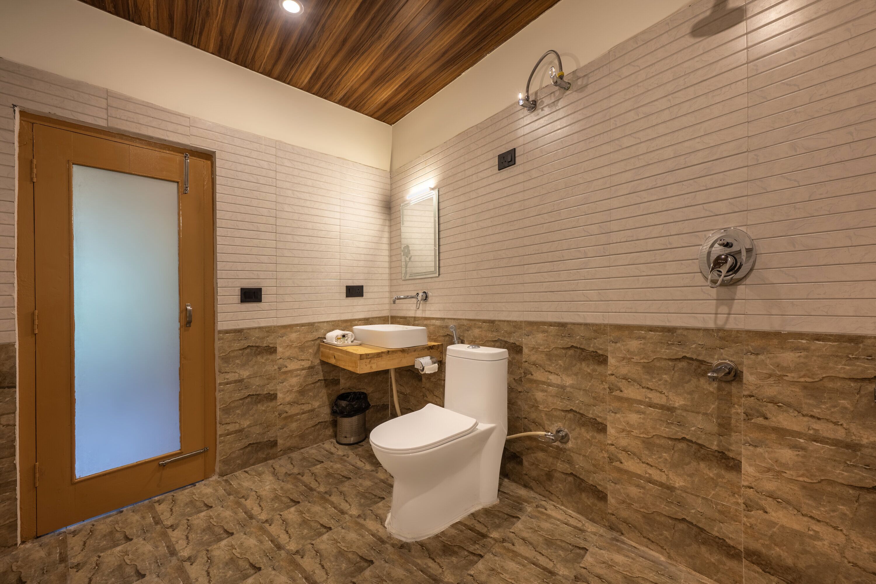 Un baño con puerta de madera, inodoro blanco, lavabo y ducha.