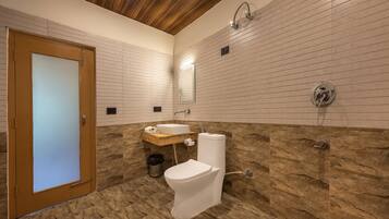 Un baño con puerta de madera, inodoro blanco, lavabo y ducha.
