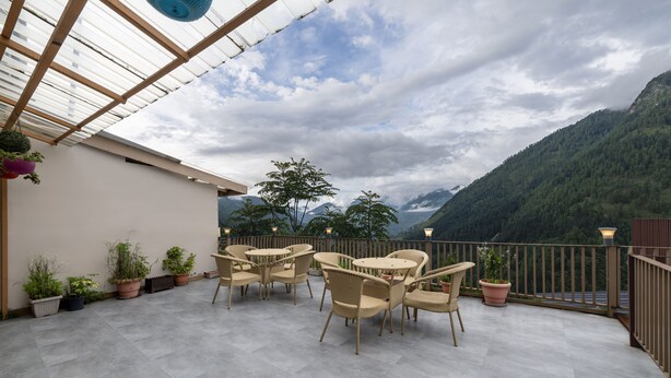 Una terraza con mobiliario exterior y plantas en macetas, con vistas a un paisaje montañoso.