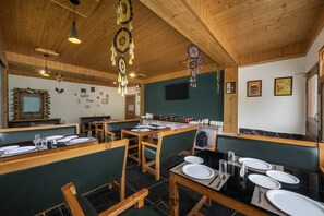 Un restaurante con interiores de madera, asientos tipo cabina verdes y piso cubierto de baldosas negras.