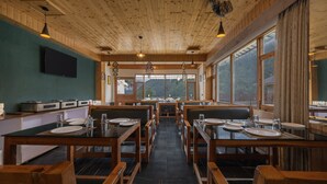 Un restaurante con interior de madera y amplios ventanales que ofrecen vistas al exterior.