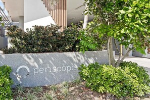 Ein Schild mit dem Wort 'Periscope' in einem modernen Gebäude, umgeben von Grünpflanzen und architektonischen Details.