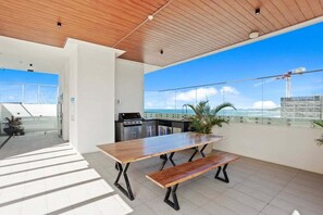 Een moderne keuken met uitzicht op de oceaan, een houten eettafel en een balkon met een hekwerk.