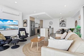 Ein stilvolles Wohnzimmer mit einer Couch, Sesseln, einem Couchtisch und einem Fernseher.
