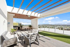 Een terras op het dak met een houten pergola, buitenmeubels en uitzicht op de skyline.
