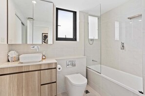 Een moderne badkamer met toilet, wastafel en douche.