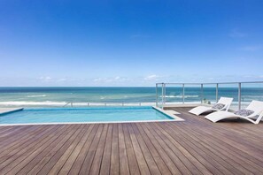 A wooden deck with a pool and lounge chairs overlooking the ocean. - Ocean View Luxury in Periscope (Gold Coast)