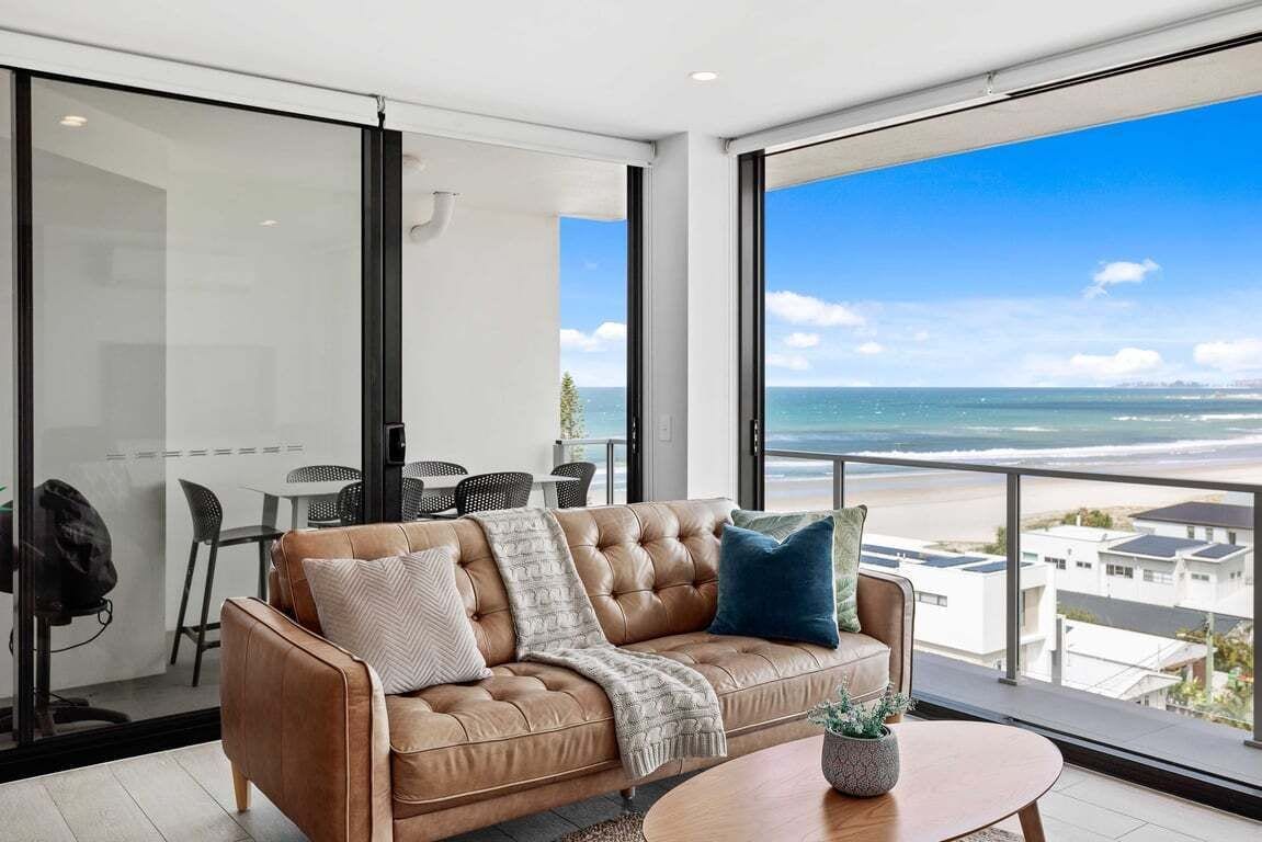 Ein modernes Wohnzimmer mit einem Ledersofa, einem Couchtisch und Blick auf den Ozean.