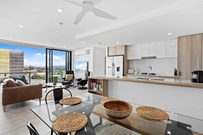 A modern kitchen with white cabinets, a built-in oven, and a large island with a sink. - Ocean View Luxury in Periscope (Gold Coast)