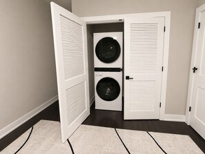 A laundry room with two stacked front-loading washing machines and a door with a handle.