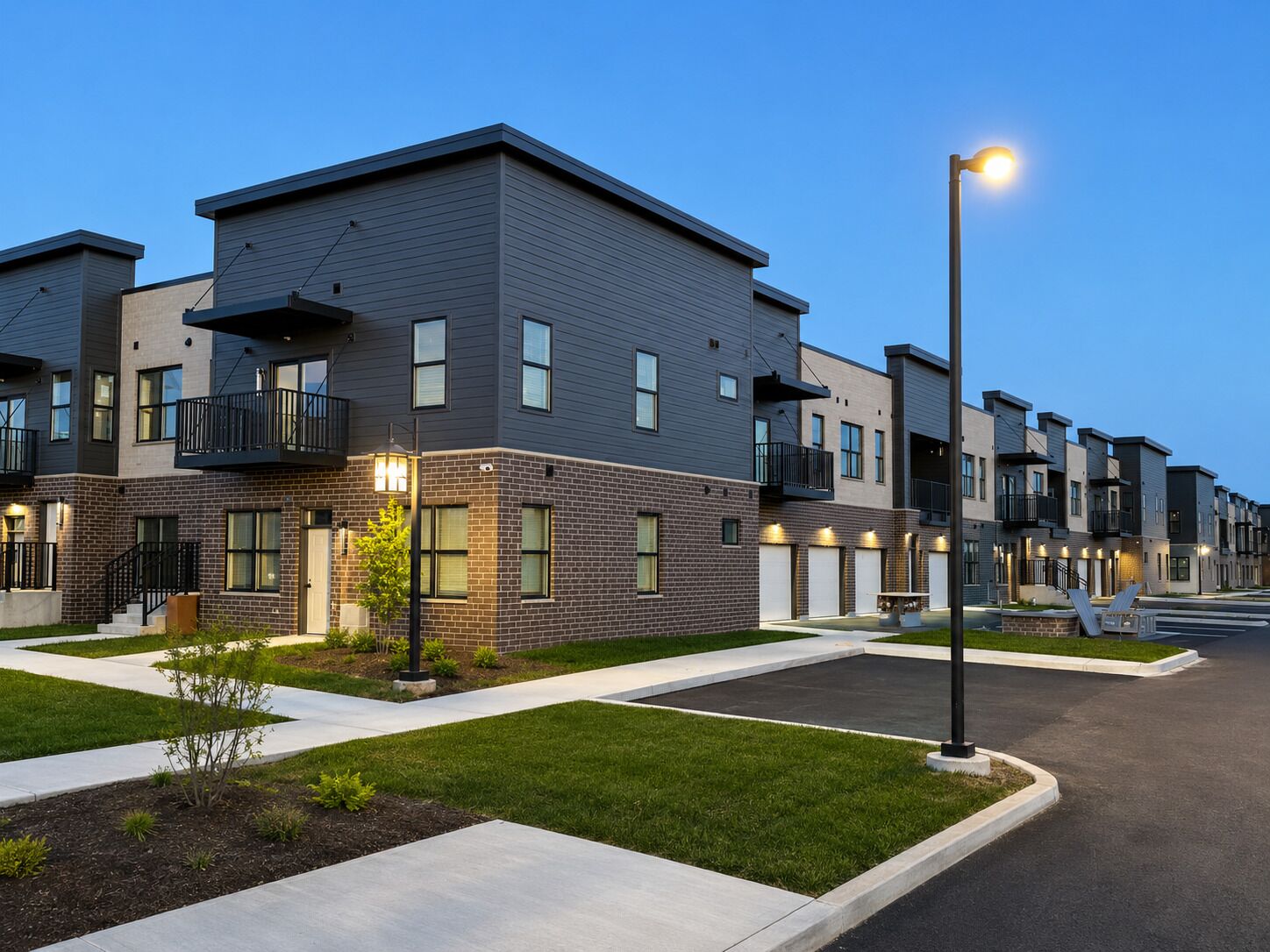 A modern residential building with a flat roof, multiple balconies, and a well-maintained lawn.