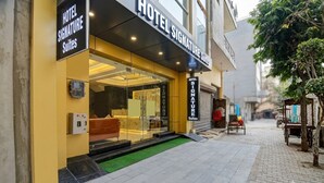 A hotel entrance with a glass facade, a reception desk, and a sign indicating 'HOTEL SIGNATURE Suites.' - Hotel Signature Suites (New Delhi)