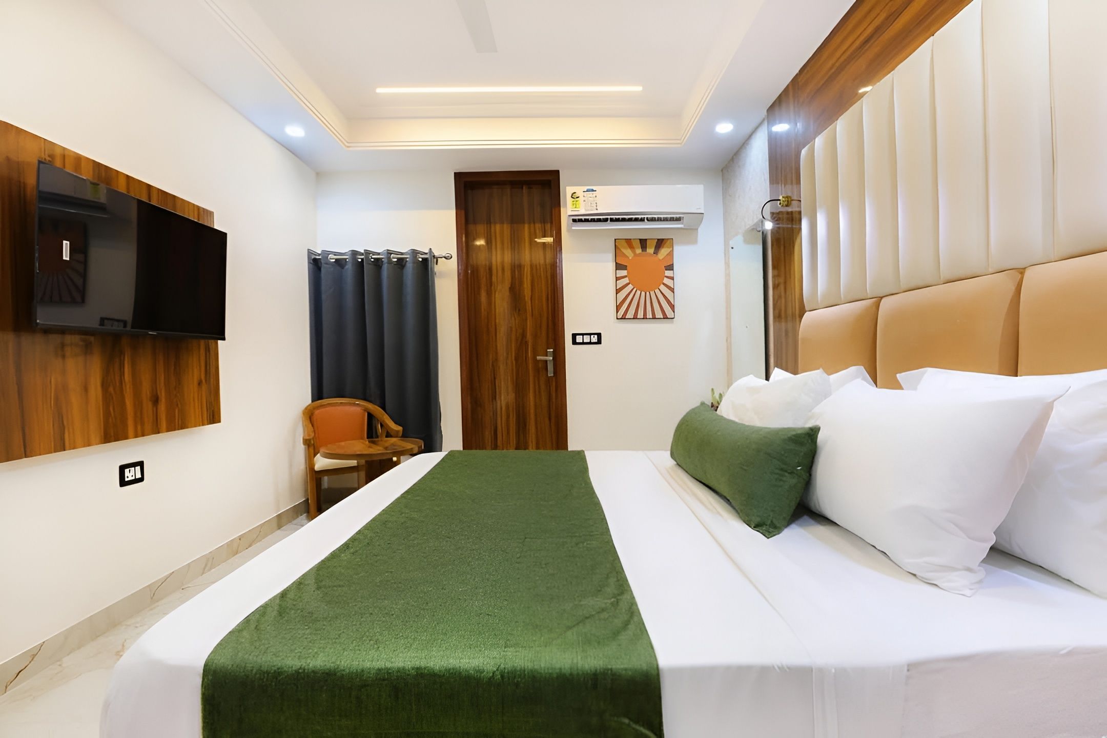 A hotel room with a bed, a television mounted on the wall, a chair, and a door.