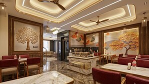 A modern restaurant with marble flooring, red upholstered seating, and decorative wall art. - Hotel Signature Suites (New Delhi)