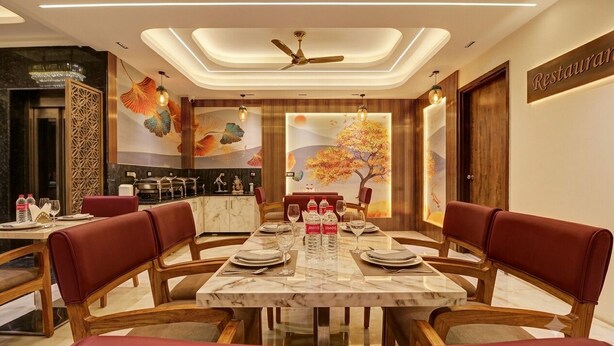 A dining area with a marble table, red upholstered chairs, and a ceiling fan. - Hotel Signature Suites (New Delhi)