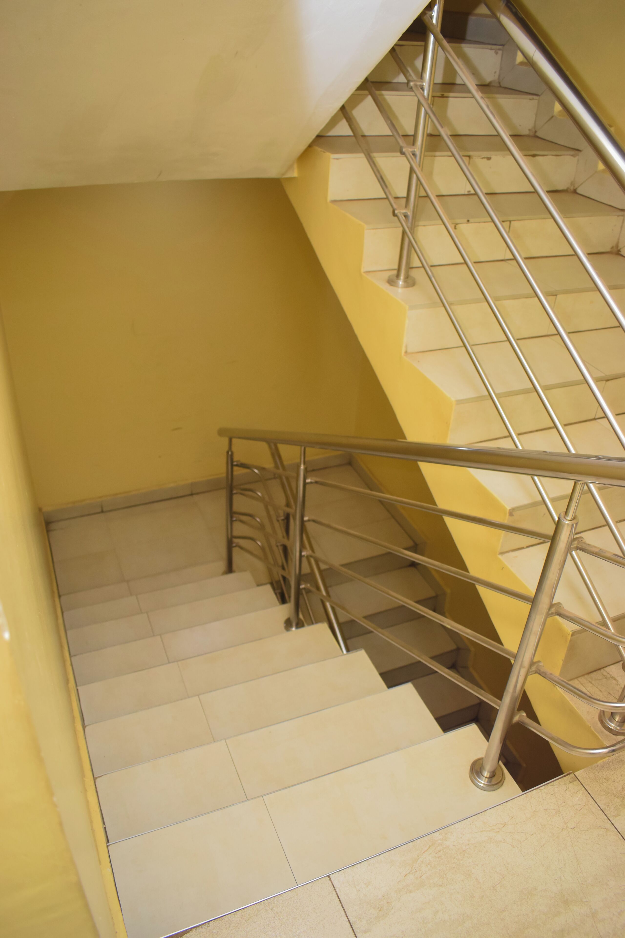 Una escalera con barandillas de metal y peldaños color crema.