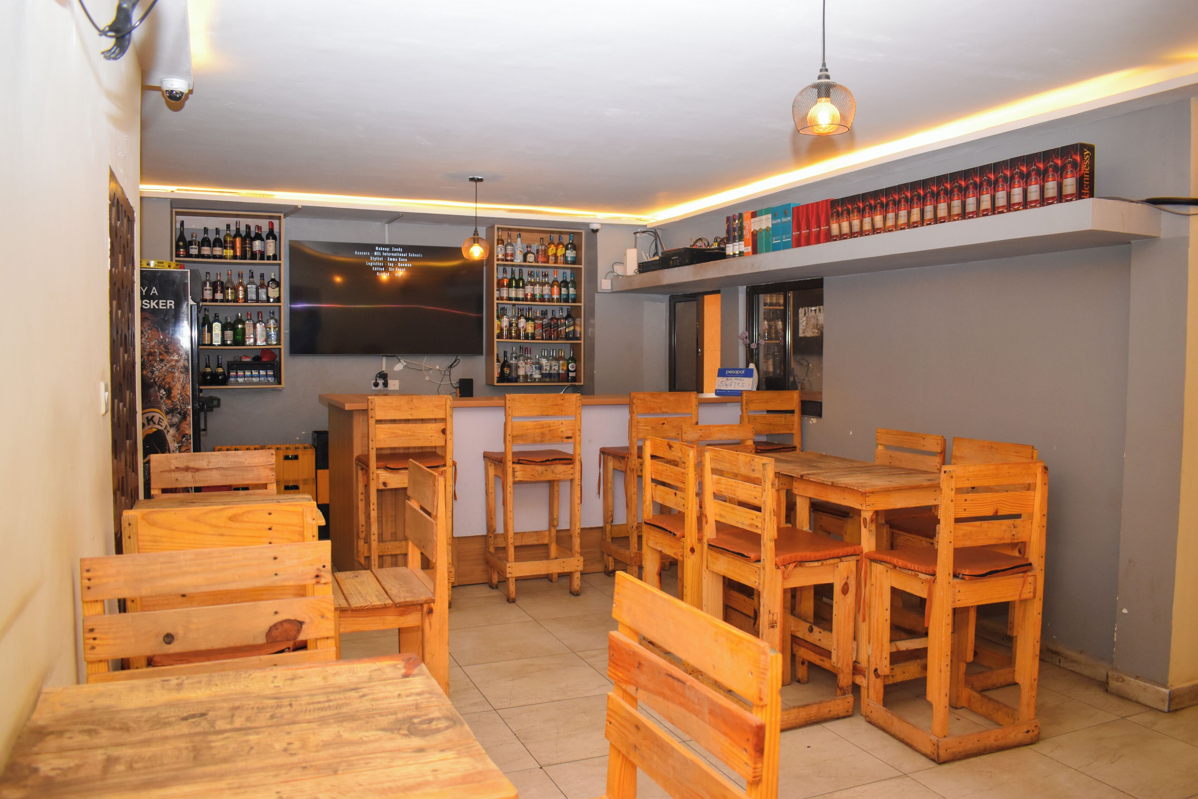 A bar area with wooden furniture, shelves with bottles, and a menu board.