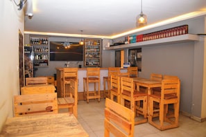 A bar area with wooden furniture, shelves with bottles, and a menu board. - Jp Resort & Spa (Nairobi)