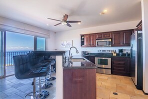 A modern kitchen with a bar area, large windows, and a view of the ocean. - 4-BR Hilltop Townhouse- Best Views in Playa Ocotal (Guanacaste Province)