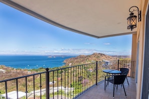 A balcony with a table and chairs, a railing, and a view of the ocean and hills. - 4-BR Hilltop Townhouse- Best Views in Playa Ocotal (Guanacaste Province)