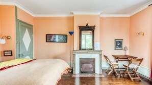 A bedroom with a bed, a fireplace, a table with chairs, and a door. - Castle with Private Park & Tennis (Anrosey)