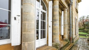A stone building with large windows, a door, and a bench outside. - Castle with Private Park & Tennis (Anrosey)
