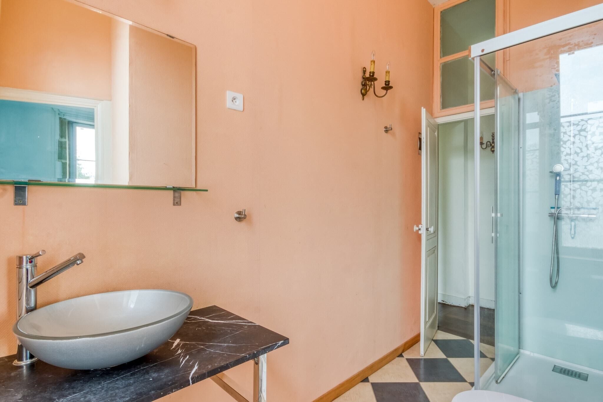 A bathroom with a large oval sink, a mirror, a shower, and a tiled floor.