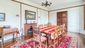 A dining room with a brick fireplace, wooden chairs, a red tablecloth, and a chandelier. - Castle with Private Park & Tennis (Anrosey)