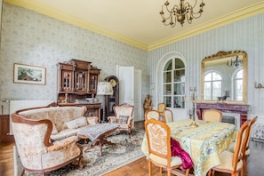 A traditional room with a dining area, a sofa set, a wooden cabinet, and a large mirror.