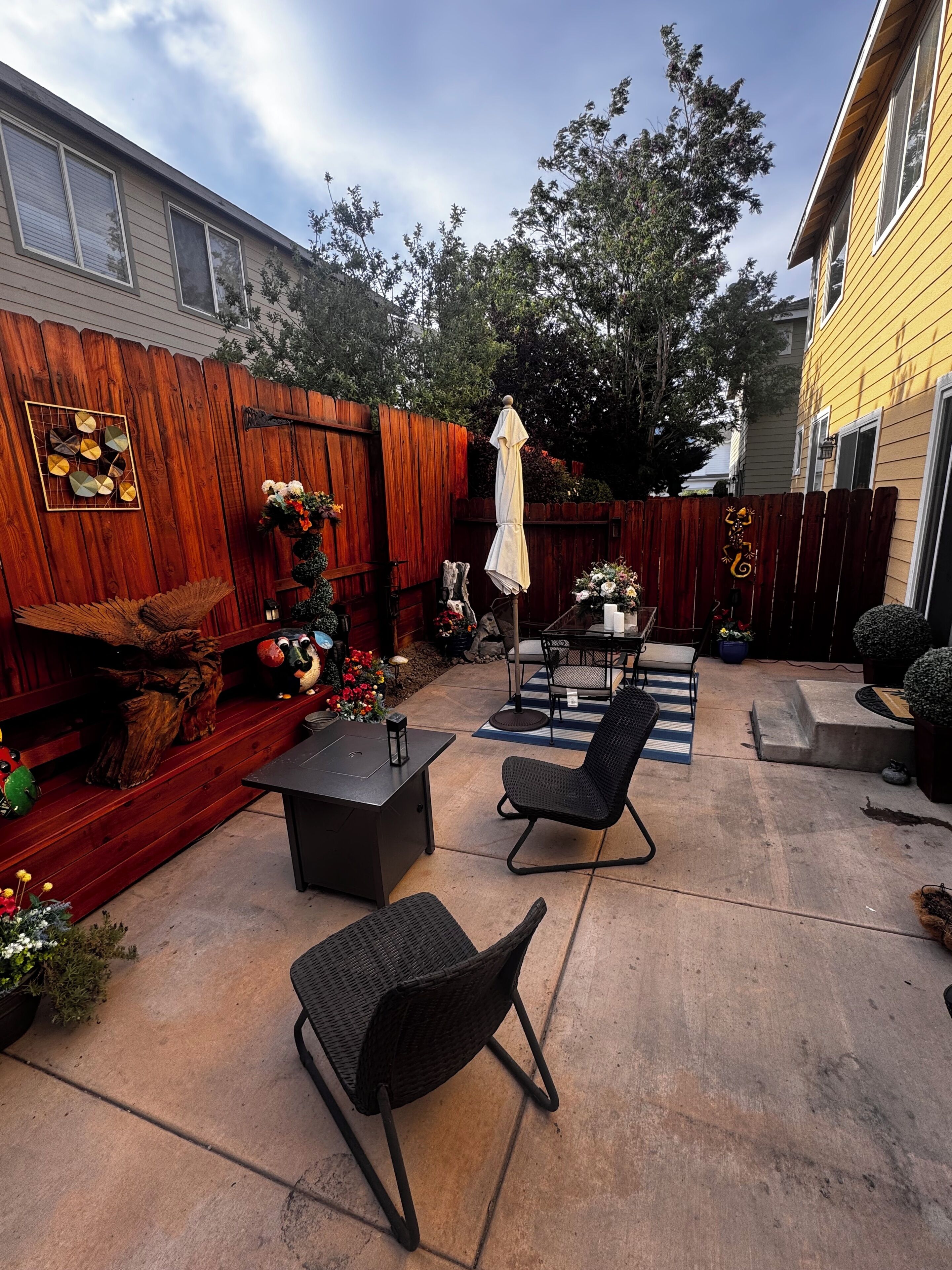 A backyard patio with a table and chairs, a wooden fence, and a decorative wall.