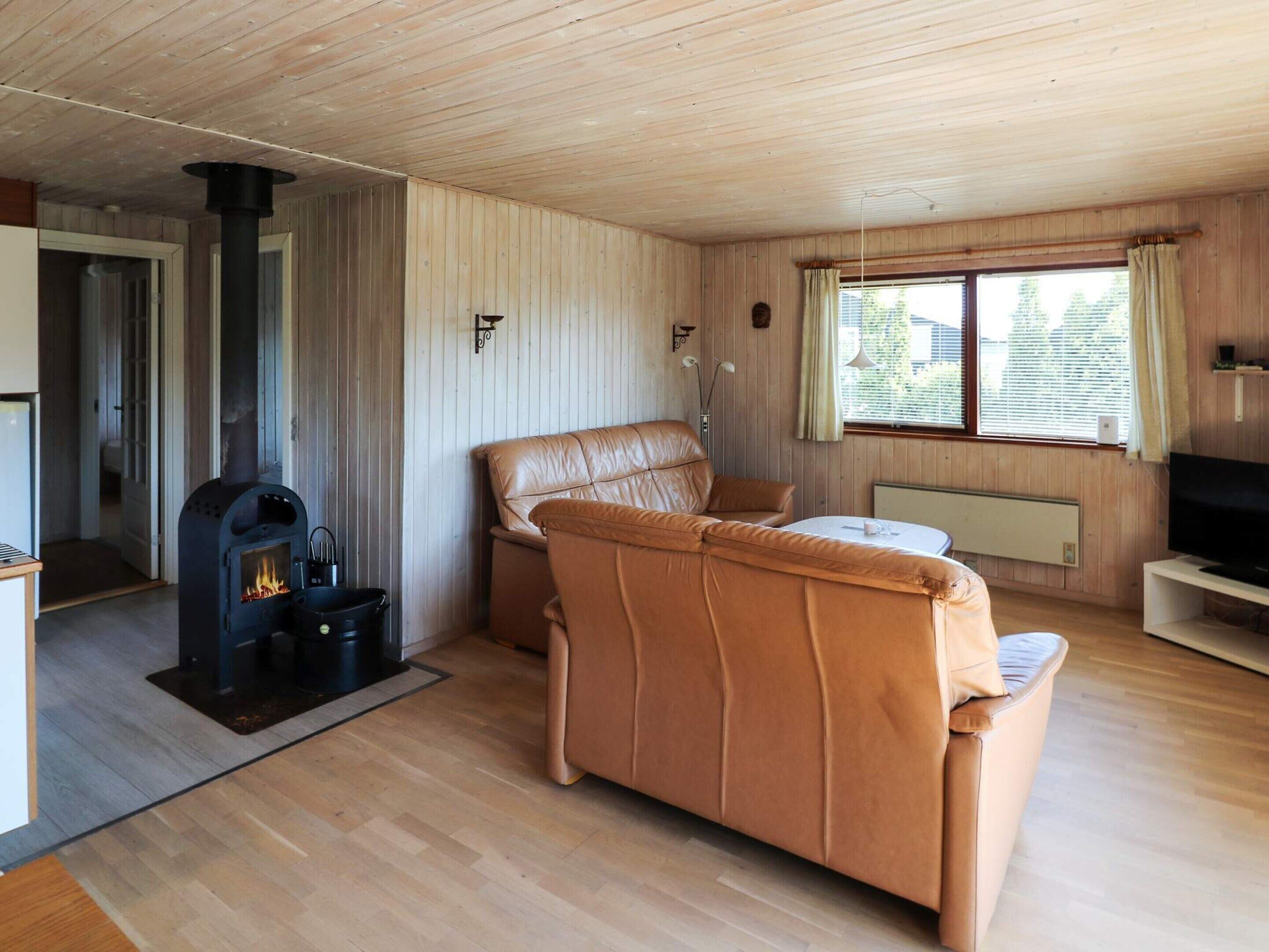 A cozy living room with a fireplace, leather sofa, and a television.