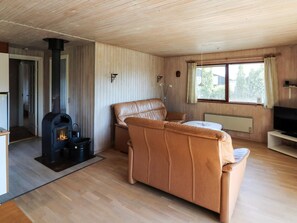 A cozy living room with a fireplace, leather sofa, and a television. - 5 Person Holiday Home in Hadsund (Hadsund)