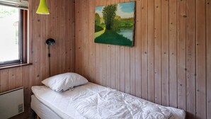 A single bed with a white mattress and pillow in a room with wooden walls. - 5 Person Holiday Home in Hadsund (Hadsund)