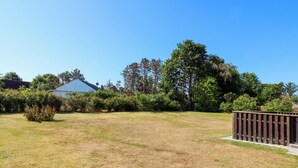A grassy yard with a wooden fence, a house, and trees in the background. - 5 Person Holiday Home in Hadsund (Hadsund)