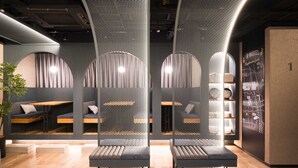 A modern interior with seating areas separated by mesh partitions, a visible staircase, and a wall-mounted map. - R Hotel Nagoya Station (Nagoya)